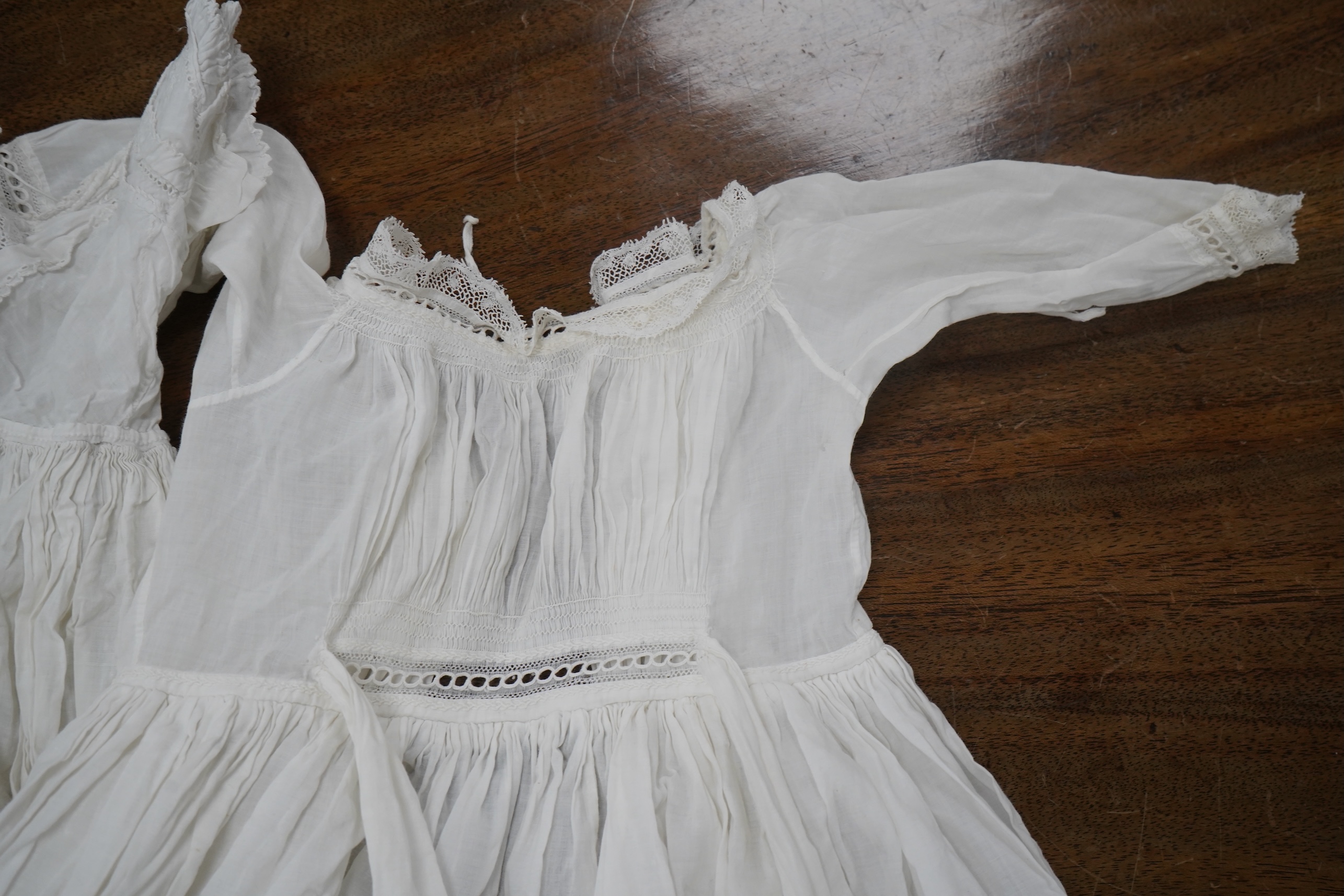 Two late 19th early 20th century long baby night gowns and two shorter baby gowns, together with a pink satin ladies full length slip and a similar cream silk stockinette slip, the bodices worked on baby dresses are embr